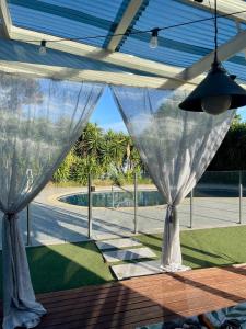 a patio with white curtains and a view of a yard at Prime Glen Huntly Beauty - 4BR Family Home w pool in Melbourne +18 photos