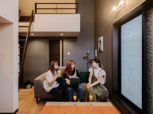 two women sitting on a couch in a living room at Reqrasサクラマチ in Kumamoto