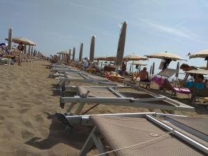 una fila di sedie a sdraio e ombrelloni in spiaggia di Meridiana, 2 Bedrooms a Caorle