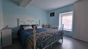 a bedroom with a bed with blue walls and a window at Les lauriers in Houlette