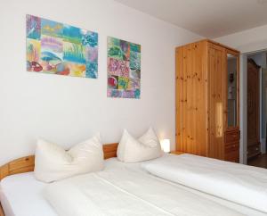 费斯恩2-Raum FeWo Siebenschläfer - Hallenbad & Sauna的卧室配有2张白色的床,墙上挂有绘画作品 更多9张照片