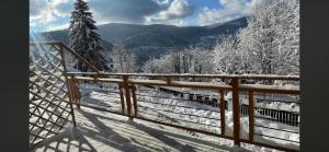 a snow covered fence with a view of the mountains at Dwupoziomowe Apartamenty Leszczyna in Ustroń