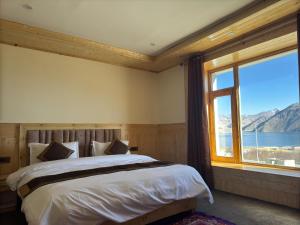 a bedroom with a bed and a large window at Bukpa Retreat - Pangong in Man