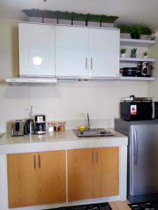 a kitchen with white cabinets and a sink and a refrigerator at CoNDOTEL DC in Dumaguete