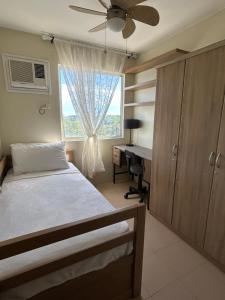 a bedroom with a bed and a desk and a window at CoNDOTEL DC in Dumaguete +21 photos