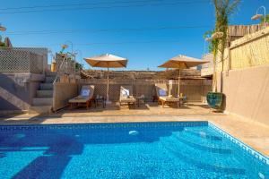 a swimming pool with patio furniture and umbrellas at Palais Tara & Spa in Marrakesh