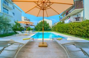 a swimming pool with an umbrella and chairs and a pool at Cozy New Apartments with Private Pool Podstrana in Podstrana