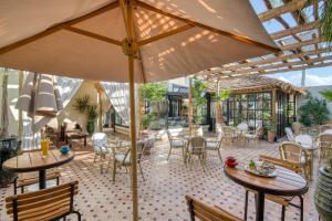 a patio with tables and chairs and an umbrella at Palais Tara & Spa in Marrakesh