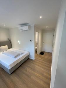 a white bedroom with a bed and a hallway at Apartments Mühl17 in Münchweiler an der Alsenz