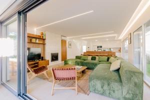 ein Wohnzimmer mit einem grünen Sofa und einem TV in der Unterkunft Botánica by Caparica Experience in Charneca + 53 Fotos