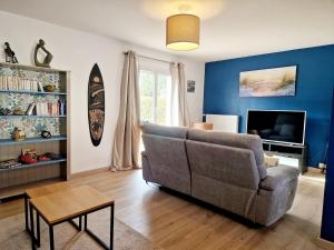 ein Wohnzimmer mit Sofa und Fernseher in der Unterkunft Les Oyats in Les Pieux