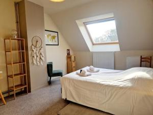 ein Schlafzimmer mit einem weißen Bett mit einem Fenster in der Unterkunft Les Oyats in Les Pieux