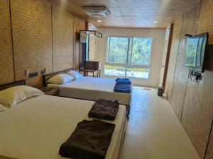 a room with three beds and a window at Gambhiraa Resorts in Kolli Hills