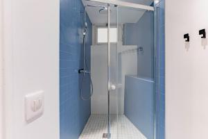 a blue bathroom with a shower with a glass door at Saint germain sartre apartment in Paris +21 photos