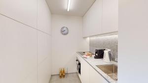 une cuisine avec des armoires blanches et une horloge au mur dans l'établissement Au Réduit 403, à Saint-Moritz