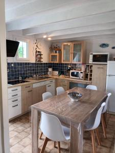 een keuken met een houten tafel en witte stoelen bij Le clos de la Galiote in Saint-Pierre-dʼOléron