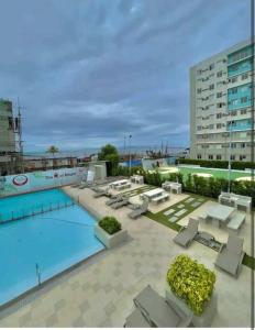 a large swimming pool with lounge chairs and a building at CoNDOTEL DC in Dumaguete