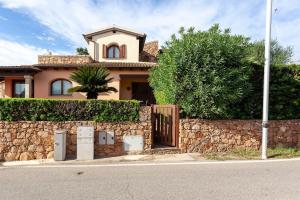 a house with a stone wall and a fence at Villetta Perla Marina 2 in San Teodoro