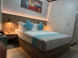a bedroom with a bed with blue and white pillows at Strand Hotel in Abu Dhabi