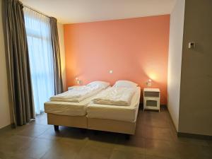 ein Schlafzimmer mit einem Bett mit einer orangefarbenen Wand in der Unterkunft Vakantiehuis de Reiger SE15 in Serooskerke