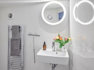Un baño blanco con lavabo y espejo. en Your Houseboat Amsterdam, en Ámsterdam