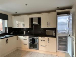 a kitchen with white cabinets and a refrigerator at Victorian Charm in Barrow in Barrow in Furness