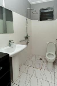 a white bathroom with a sink and a toilet at Akeva in Brazzaville