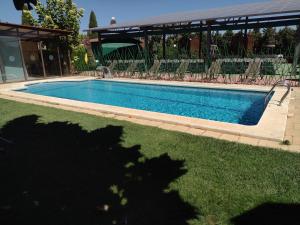 a swimming pool in a yard with chairs around it at Hotel Boutique Palacio de la Serna in Ballesteros de Calatrava