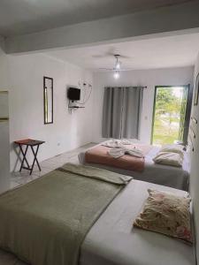 a bedroom with two beds and a tv on the wall at Pousada Vale Do Aijalom in Cabo Frio