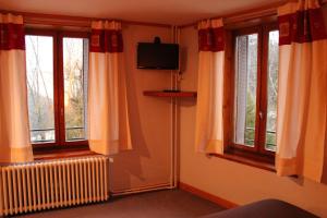 a living room with two windows and a television at La Ferme du Bois Barbu in Villard-de-Lans