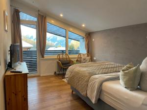 a bedroom with a bed and a large window at NEST'L Appartements & Zimmer in Mösern