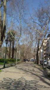 a tree lined street with people walking down the sidewalk at Casa Nossa in Lisbon