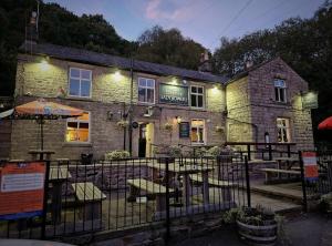a building with an umbrella and chairs in front of it at The Ladybower Inn in Bamford