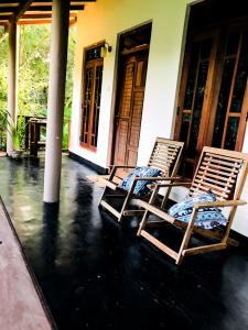 Dos sillas sentadas en el porche de una casa. en Sh li, en Sigiriya