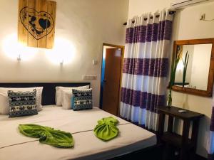 1 dormitorio con 1 cama con toallas verdes en Sh li, en Sigiriya