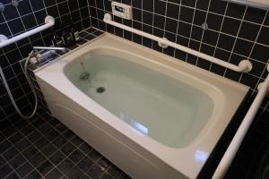 a bath tub in a bathroom with black tiles at 浮遊のいえ 建築家原広司の住宅作品 Floating House A Private Stay in the Art of Architect Hiroshi Hara in Joetsu