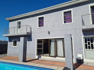 a white house with a swimming pool in front of it at Pemba's residence in Cape Town