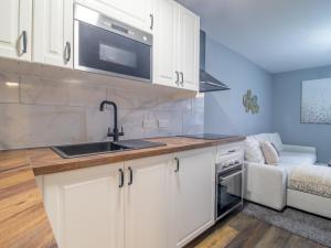 a kitchen with white cabinets and a sink and a couch at Pass the Keys Happy Haven Home, West End in Glasgow