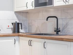 a kitchen with white cabinets and a sink at Pass the Keys Happy Haven Home, West End in Glasgow