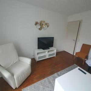 un soggiorno con un divano bianco e una televisione di Maison a Ambrault