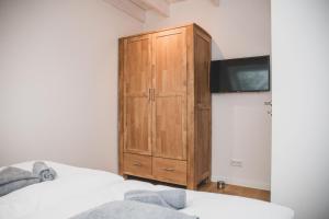 a bedroom with a wooden cabinet next to two beds at Van Senden 1 Zwaantje in Krummhörn