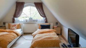 ツィングストにあるKormoran Wohnung 13のベッド2台と窓が備わる屋根裏部屋です。