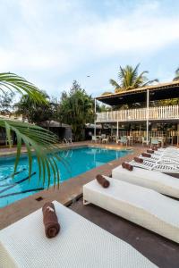 a resort with a swimming pool with white lounge chairs at Marbela Beach Resort in Morjim