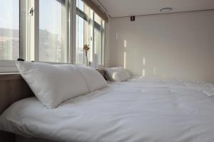 a bed with white pillows in a room with a window at Manso Hostel in DDP in Seoul +34 photos