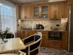 a kitchen with wooden cabinets and a table with chairs at V A z A T A apartment in Ruse
