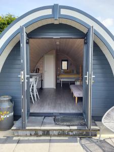 an open door of a blue shed with a table at Ballyhemlin Pods - Haw thorn in Bushmills