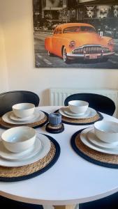 a table with plates and bowls and a orange car on the wall at Tropical Sun Homes - Beautiful spacious 3 bed home in a serene environment with free parking for 2 cars in Manchester
