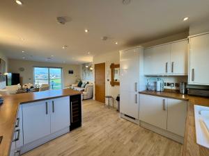 a kitchen with white cabinets and a living room at Gwel Y Bae-2 Bed-en-suite-Lift-Pet friendly in Trearddur