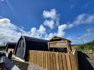 a black shed with a wooden fence next to it at Ballyhemlin pods - Blackthorn in Bushmills +12 photos