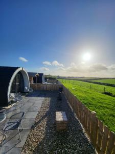 a patio with chairs and a tent and a field at Ballyhemlin pods - Blackthorn in Bushmills